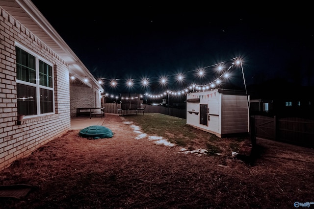 yard at twilight with a storage shed and a trampoline