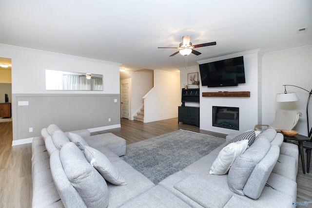 living room featuring ceiling fan, a fireplace, ornamental molding, and hardwood / wood-style floors