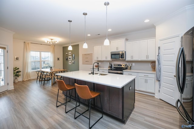 kitchen featuring decorative light fixtures, sink, an island with sink, stainless steel appliances, and white cabinets