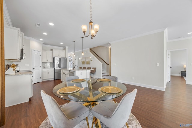 dining area with ornamental molding, sink, dark hardwood / wood-style floors, and an inviting chandelier