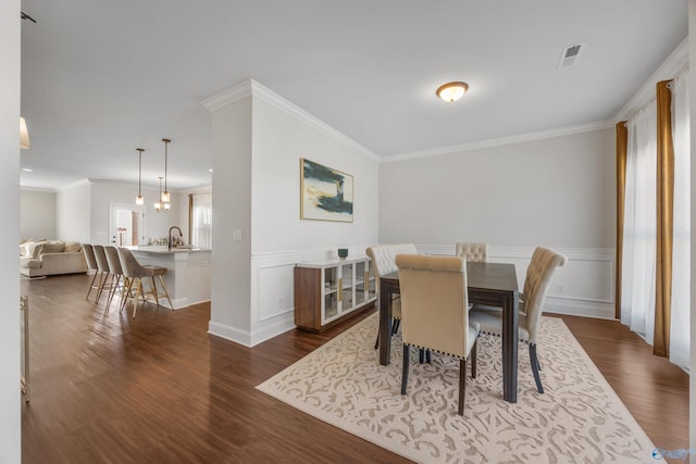 dining area featuring sink, ornamental molding, and dark hardwood / wood-style flooring