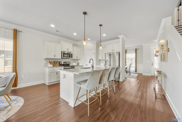 kitchen with sink, an island with sink, dark hardwood / wood-style flooring, white cabinetry, and stainless steel appliances