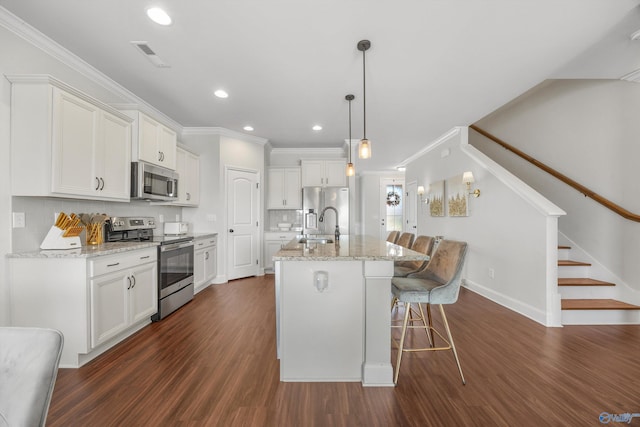 kitchen featuring dark wood-type flooring, appliances with stainless steel finishes, a kitchen island with sink, and white cabinets