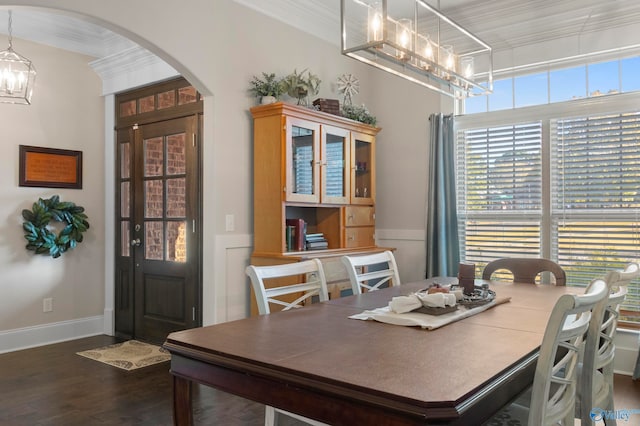 dining space with arched walkways, a notable chandelier, baseboards, dark wood-style floors, and crown molding