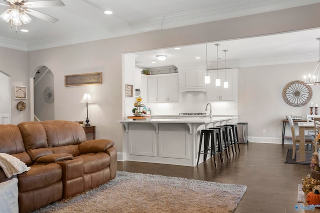 living room with dark wood-style floors, arched walkways, ornamental molding, and baseboards