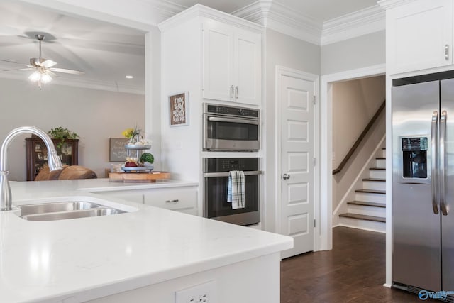 kitchen featuring dark wood finished floors, white cabinets, appliances with stainless steel finishes, crown molding, and a sink