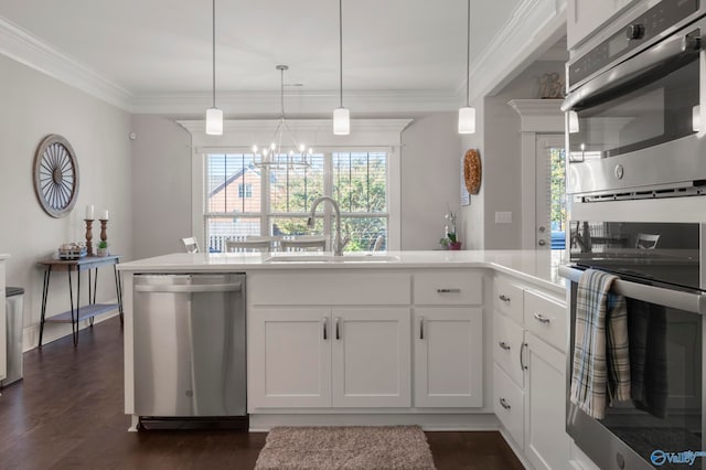 kitchen featuring stainless steel appliances, a sink, white cabinets, a wealth of natural light, and decorative light fixtures