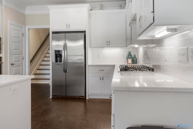 kitchen with light stone counters, white cabinetry, stainless steel appliances, and crown molding