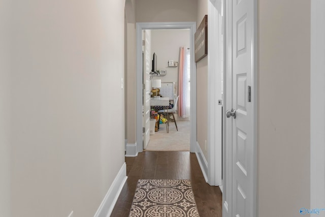 hallway featuring dark wood-style flooring and baseboards