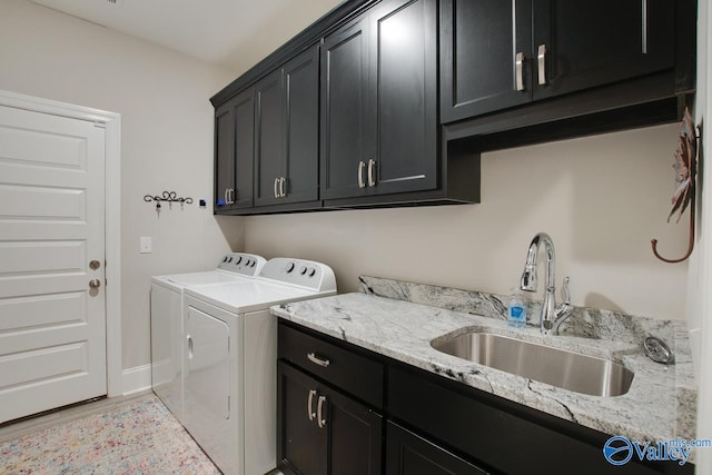 laundry room with cabinet space, light wood finished floors, baseboards, washing machine and clothes dryer, and a sink