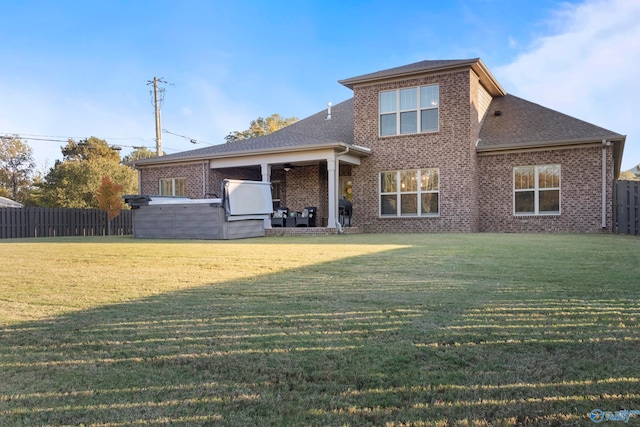 back of house with brick siding, a lawn, and fence