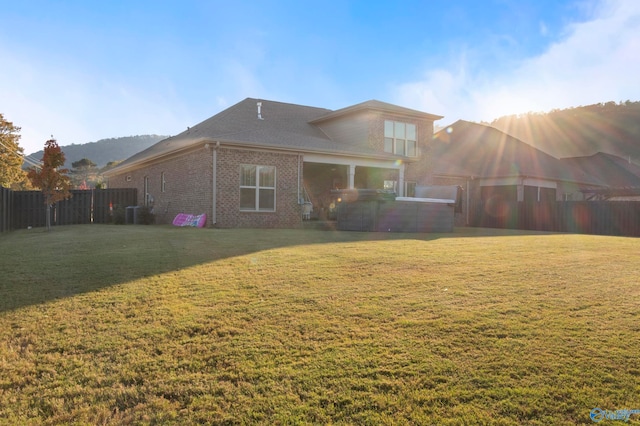 back of property with a yard, brick siding, and fence