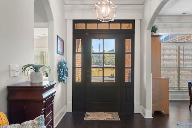 foyer entrance with dark wood-type flooring, a chandelier, and crown molding