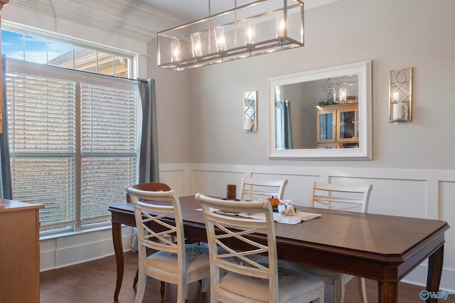 dining area featuring a wainscoted wall, ornamental molding, wood finished floors, and a decorative wall