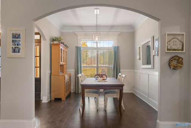 dining space with a decorative wall, dark wood-style flooring, wainscoting, and crown molding