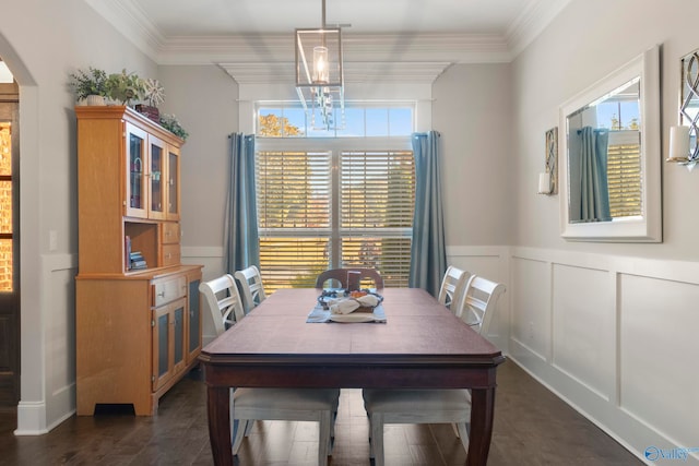 dining area with arched walkways, a chandelier, a decorative wall, wainscoting, and crown molding