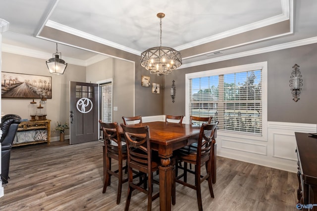 dining space with dark hardwood / wood-style floors, an inviting chandelier, crown molding, and a tray ceiling