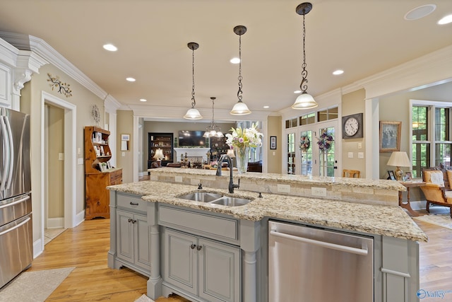 kitchen featuring crown molding, appliances with stainless steel finishes, a sink, gray cabinets, and open floor plan