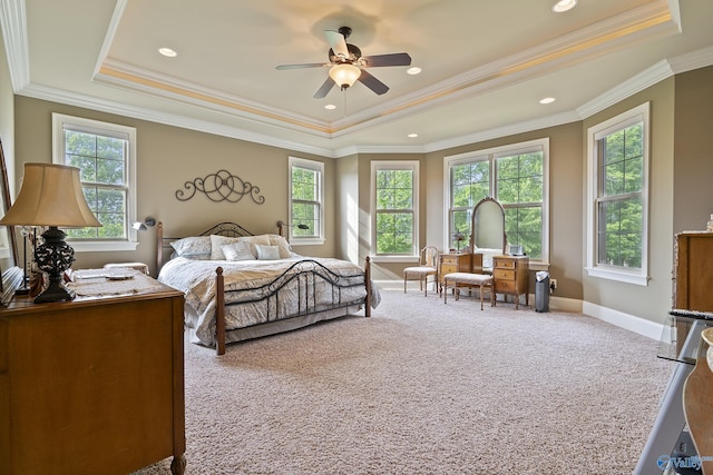 carpeted bedroom featuring a raised ceiling, baseboards, ornamental molding, and ceiling fan