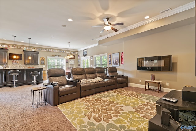 carpeted living room with visible vents, ceiling fan with notable chandelier, bar area, ornamental molding, and recessed lighting
