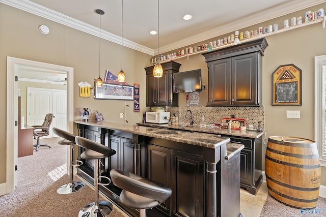bar with crown molding, light colored carpet, hanging light fixtures, decorative backsplash, and white microwave