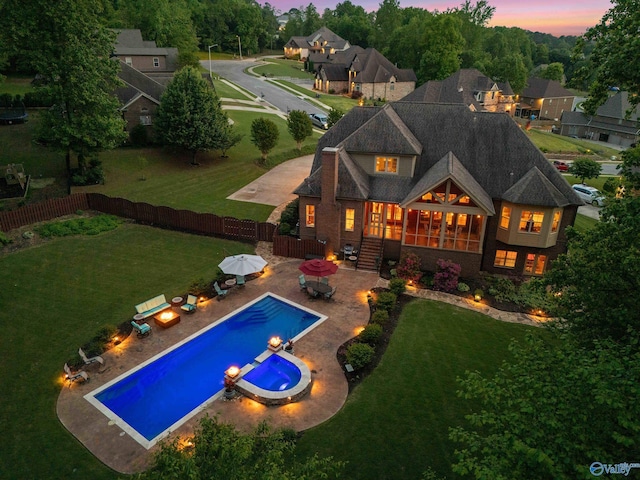 back of property featuring a fenced backyard, a patio, a yard, and a pool with connected hot tub