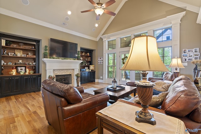 living room with high vaulted ceiling, a glass covered fireplace, ceiling fan, and light wood-type flooring