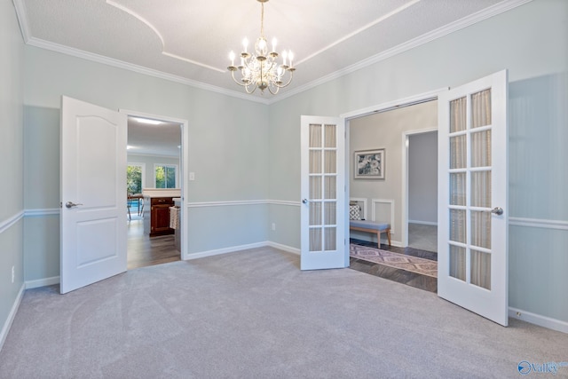 carpeted spare room featuring crown molding, french doors, a textured ceiling, and an inviting chandelier