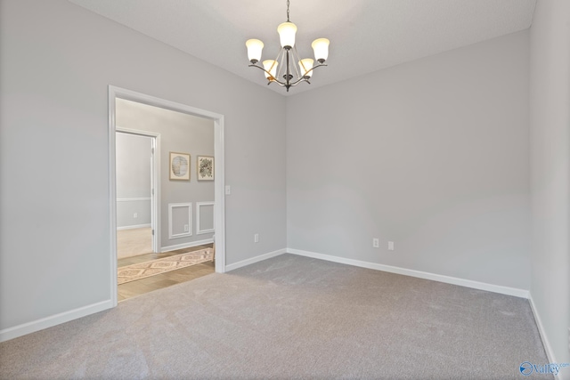 carpeted empty room with a notable chandelier