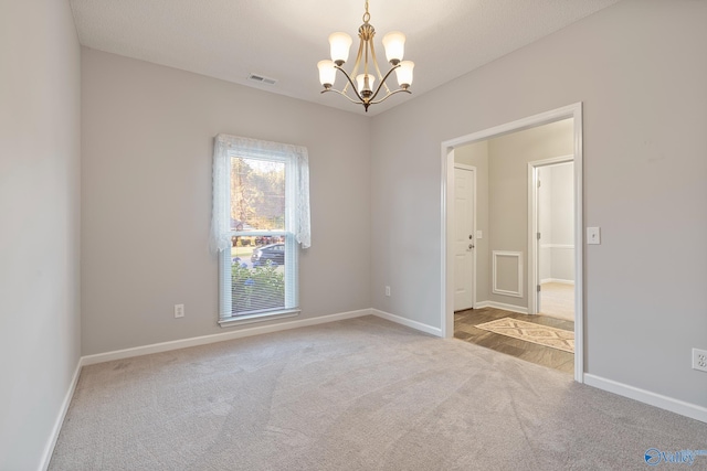 empty room featuring light carpet and an inviting chandelier