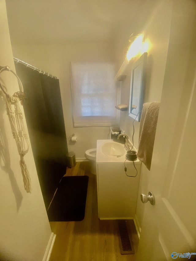 bathroom with visible vents, toilet, vanity, wood finished floors, and baseboards