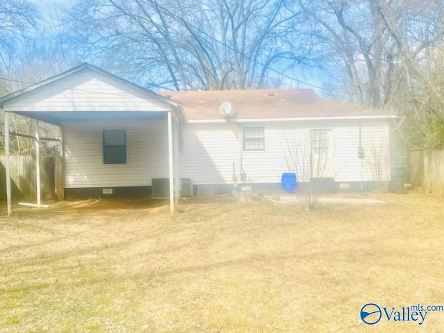 rear view of property featuring a carport, crawl space, a lawn, and fence