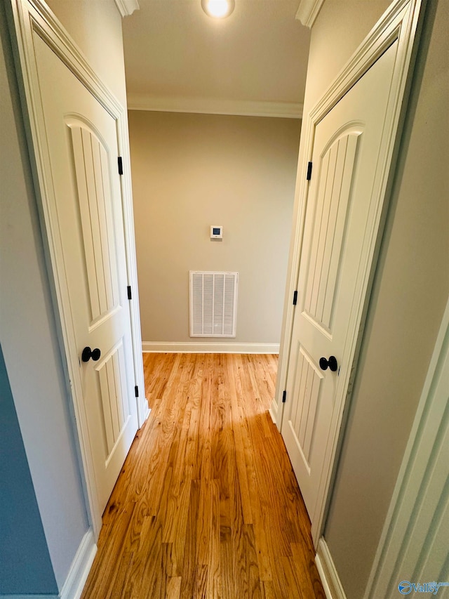 hall featuring crown molding and light hardwood / wood-style floors