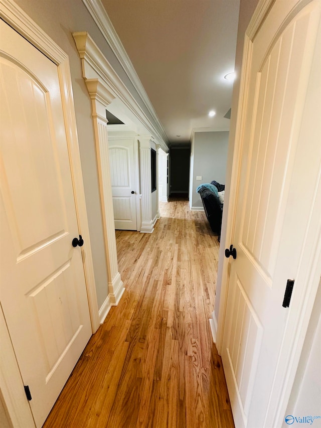 hall with ornamental molding and light hardwood / wood-style flooring