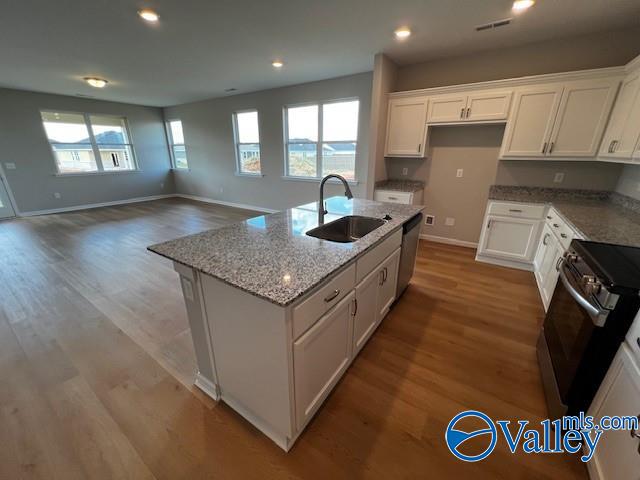 kitchen featuring appliances with stainless steel finishes, sink, hardwood / wood-style flooring, white cabinetry, and an island with sink