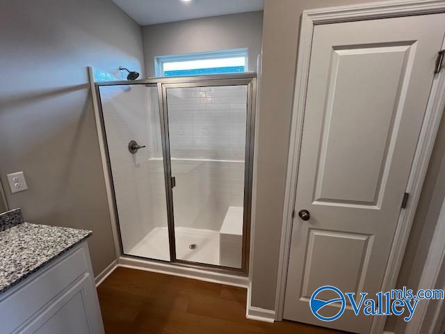 bathroom with hardwood / wood-style floors, vanity, and an enclosed shower