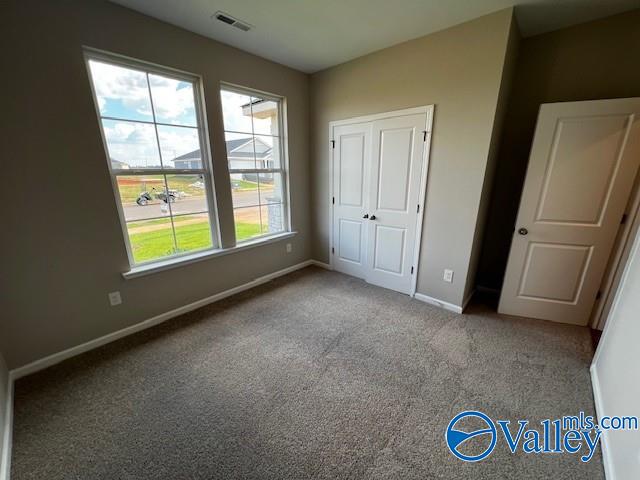 unfurnished bedroom featuring multiple windows and light colored carpet