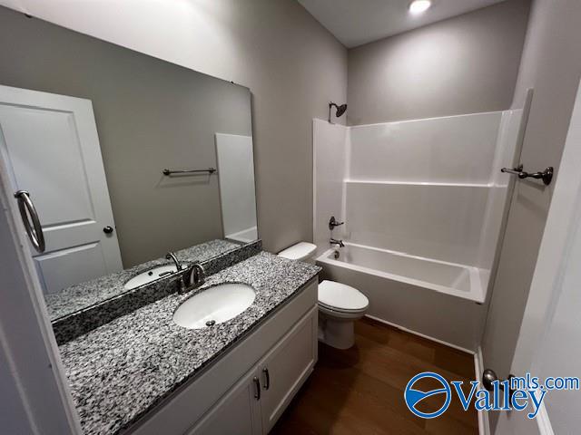 full bathroom with hardwood / wood-style flooring, vanity, toilet, and shower / tub combination