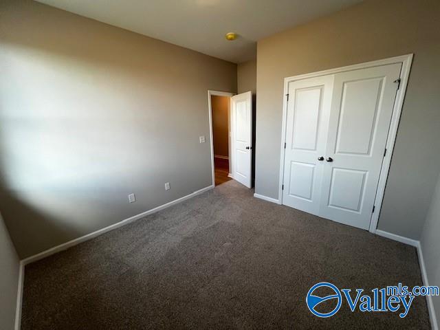 unfurnished bedroom featuring dark carpet and a closet