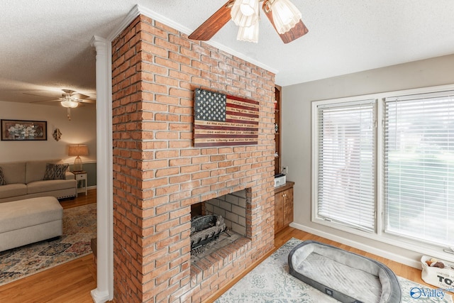 living room with a brick fireplace, crown molding, a textured ceiling, and light wood-type flooring