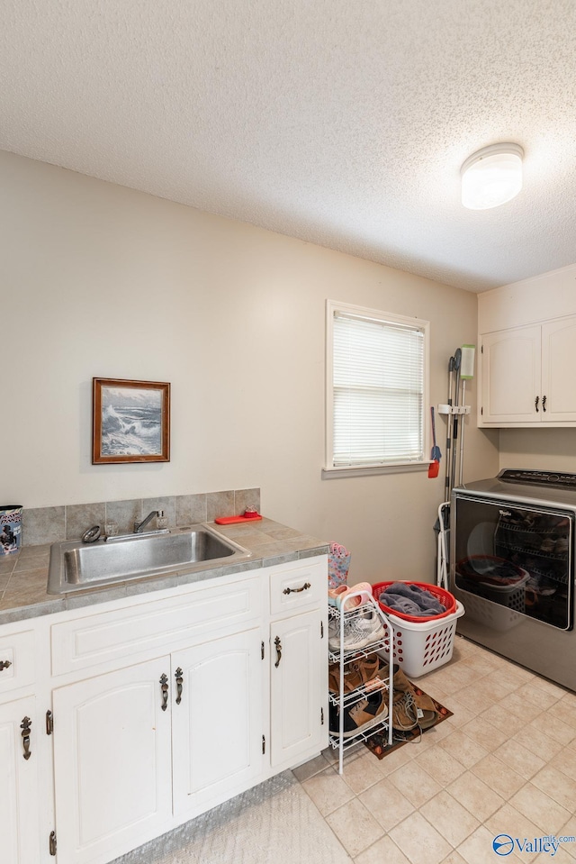 laundry area featuring cabinets, a textured ceiling, separate washer and dryer, and sink