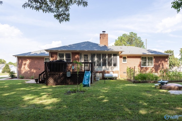 rear view of house with a yard, a wooden deck, and a sunroom