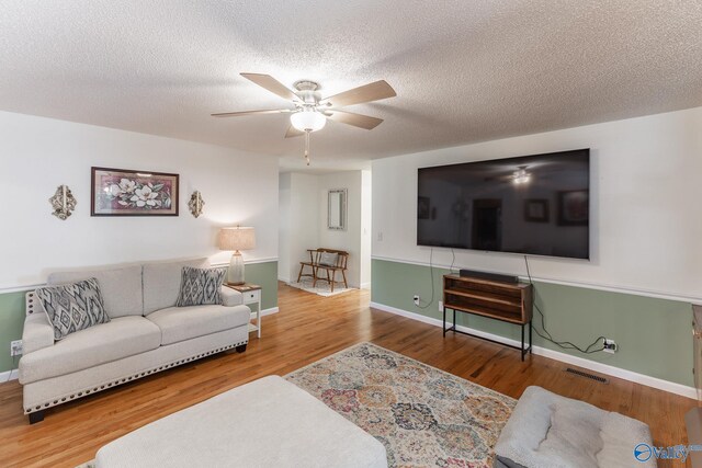 living room featuring a fireplace, light hardwood / wood-style floors, a textured ceiling, and ornamental molding