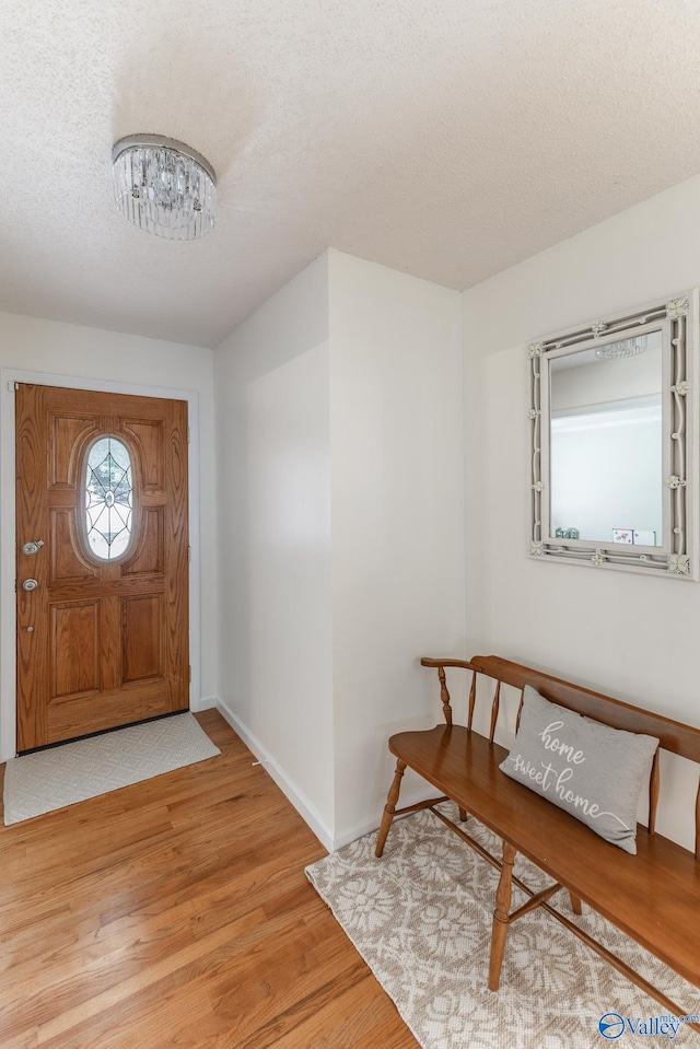 foyer entrance with a textured ceiling, hardwood / wood-style flooring, and a notable chandelier