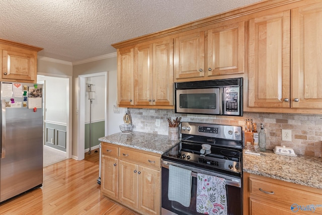 kitchen with light stone countertops, ornamental molding, tasteful backsplash, light hardwood / wood-style floors, and stainless steel appliances