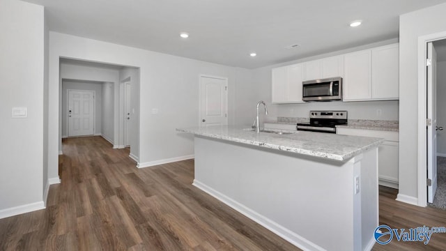 kitchen with a center island with sink, stainless steel appliances, dark hardwood / wood-style floors, white cabinets, and sink