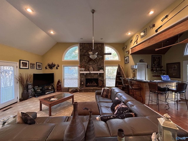 living room with a stone fireplace, high vaulted ceiling, and ceiling fan