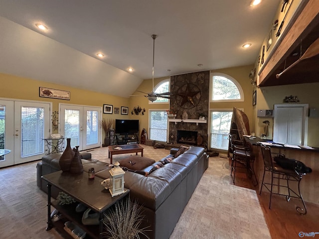 living room with french doors, ceiling fan, a fireplace, and high vaulted ceiling