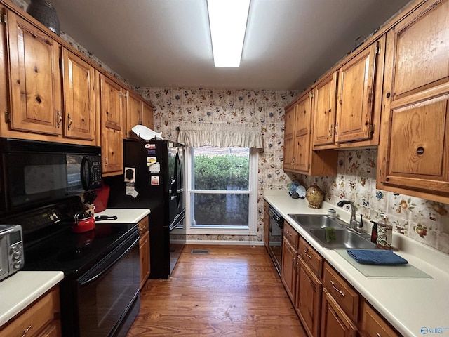 kitchen with tasteful backsplash, sink, hardwood / wood-style flooring, and black appliances