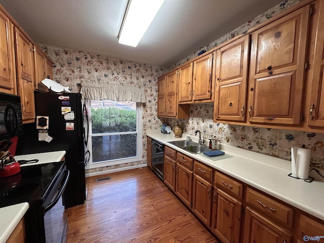 kitchen with sink, black appliances, and light wood-type flooring